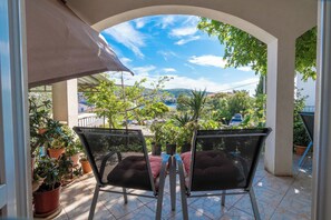 A covered outdoor seating area with chairs and potted plants. - Apartments Zlatka (Okrug)