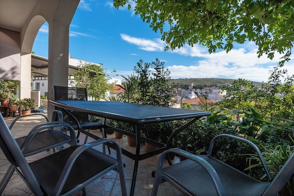 Una mesa y sillas al aire libre, con vistas a un pueblo y colinas al fondo.