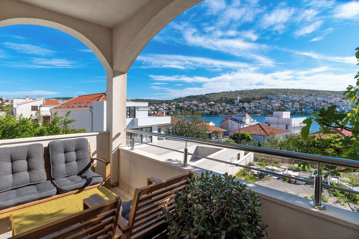 A balcony with a view of a town and a body of water.