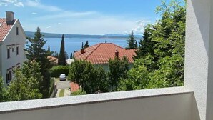 A balcony with a view of a lake, buildings, and trees. - Apartments Mia (Crikvenica)