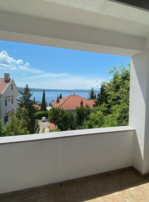 Ein Balkon mit Blick auf einen See, Gebäude und Bäume.