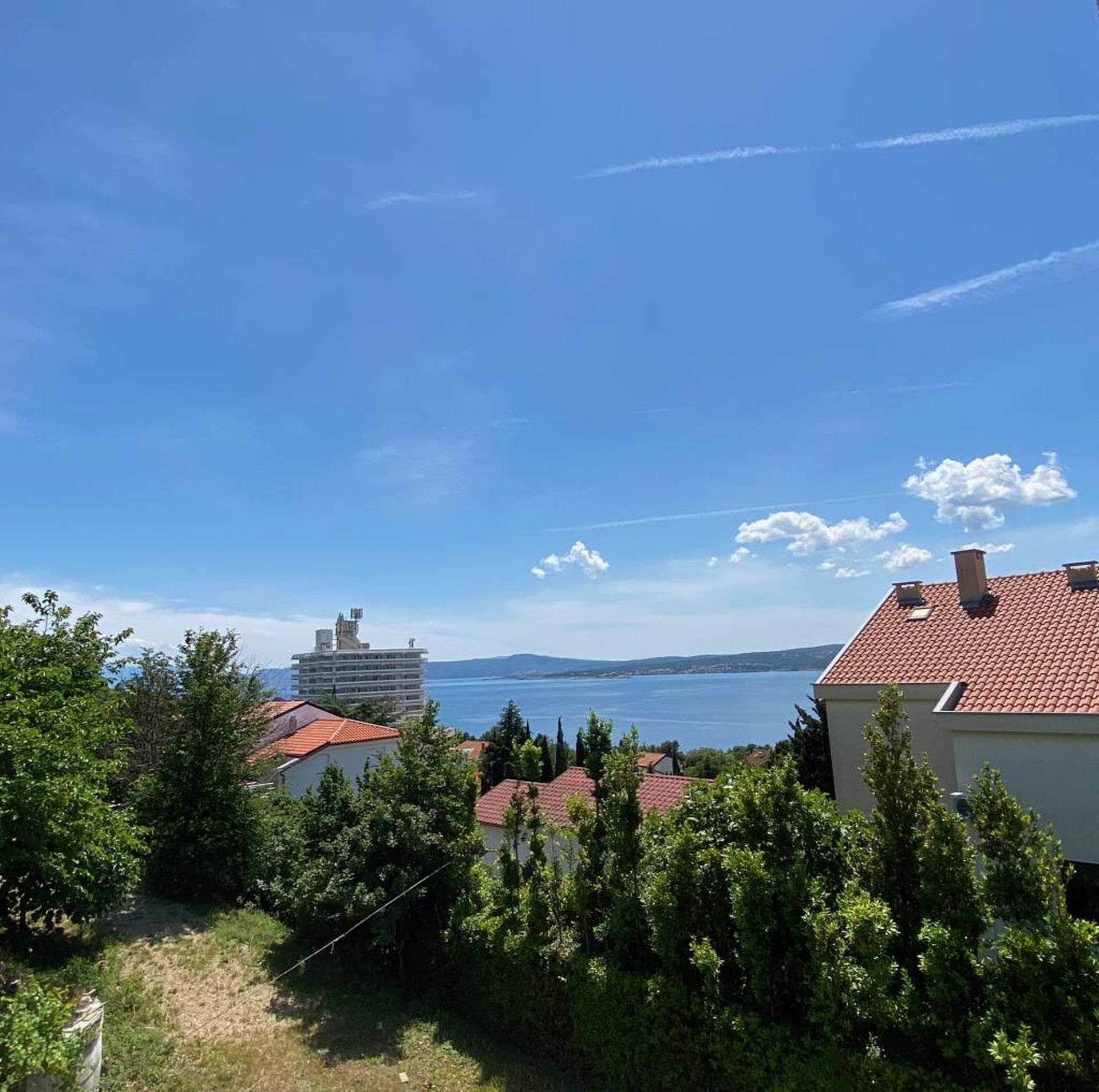 Blick auf die Küste mit Gebäuden, Bäumen und blauem Himmel.