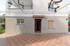 A building with a tiled patio, a door, and a window. - Apartment Ljubica (Rab)