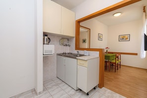 A compact kitchen with a microwave, stove, sink, and cabinets. - Apartment Ljubica (Rab)