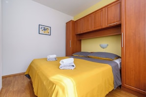 A bedroom with a bed, wooden wardrobe, and a wall-mounted light fixture. - Apartment Ljubica (Rab)