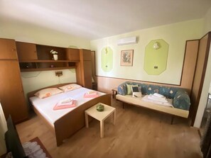 Ein Zimmer mit einem Bett, einer Couch, einem kleinen Tisch und einer Wandklimaanlage.