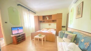 A room with a bed, a TV, a sofa, and a small table. - Apartments Fran (Crikvenica)