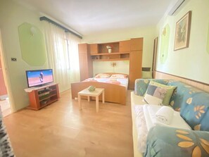 Ein Zimmer mit einem Bett, einem Fernseher, einer Couch und einem kleinen Tisch.