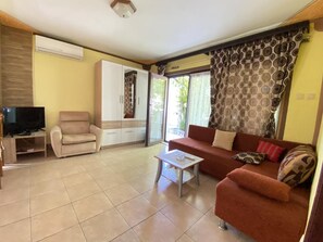 Ein Wohnzimmer mit Sofa, Sesseln, Fernseher und Schrank.