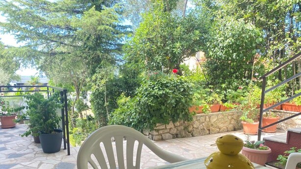 An outdoor patio with a table, chairs, potted plants, and a yellow lantern. - Apartments Fran (Crikvenica)