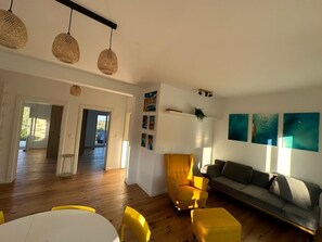 Ein großzügiger Wohnbereich mit einer Couch, einem gelben Sessel und einem Esstisch.
