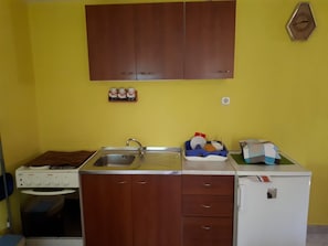 Eine Küche mit Holzschränken, einer Spüle, einem Herd und einem Kühlschrank.
