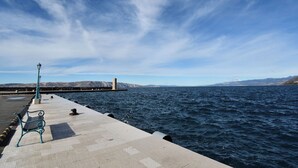 A pier with a bench, a lamp post, and a lighthouse in the distance. - Apartment Sasa (Senj)