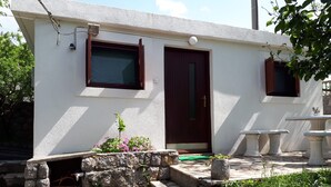 A small building with a stone staircase leading to a door, a window, and a small outdoor seating area. - Apartment Sasa (Senj)