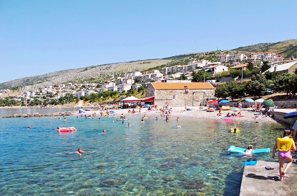Eine Küstenstadt mit klarem Wasser, einem Strand und Gebäuden an einem Hügelhang.
