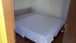 A room with a bed, a wooden headboard, a door, and a light switch on the wall. - Apartment Sasa (Senj)