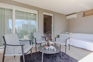A modern hotel room with a bed, two armchairs, a small table with a bowl of fruit and a bottle, and a large window with curtains. - Apartment Sea View Garden (Split)