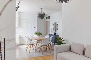 A modern dining area with a round table, white chairs, and a potted plant. - Apartment Sea View Garden (Split)