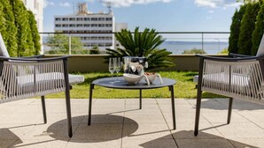 Een terras met twee rieten stoelen, een klein rond tafeltje en een schaal fruit.