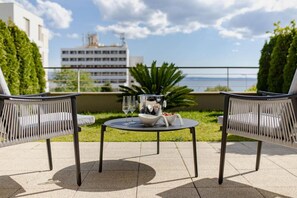 A terrace with two wicker chairs, a small round table, and a bowl of fruit. - Apartment Sea View Garden (Split)