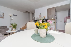 Ein modernes Wohnzimmer mit einem runden Tisch, einer Couch, einer Lampe und einer Treppe.