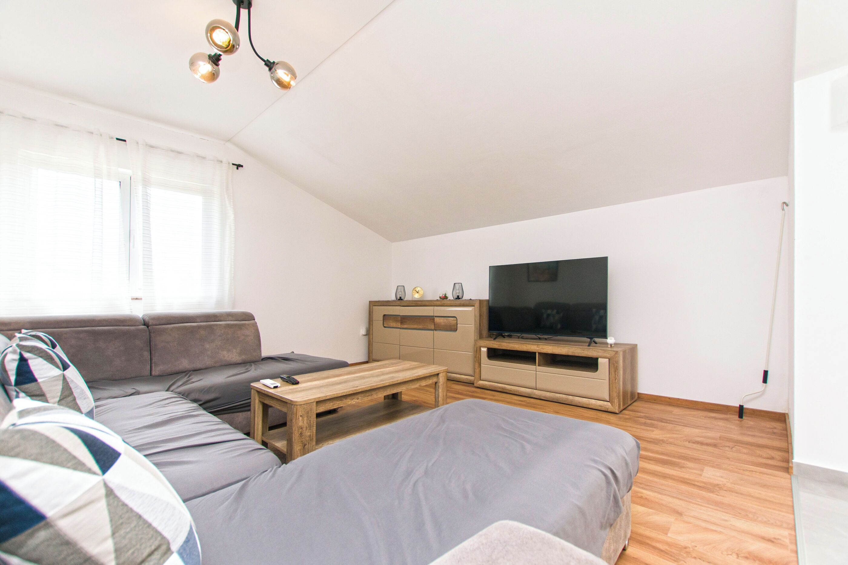 A modern living room with a sofa, a coffee table, a TV, and a wooden cabinet.