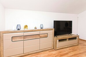 Ein modernes Wohnzimmer mit einer Holzeinrichtungsanlage, einem Flachbildfernseher und dekorativen Accessoires.