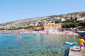 Eine Küstenstadt mit klarem Wasser, einem Strand und Gebäuden an einem Hügelhang.