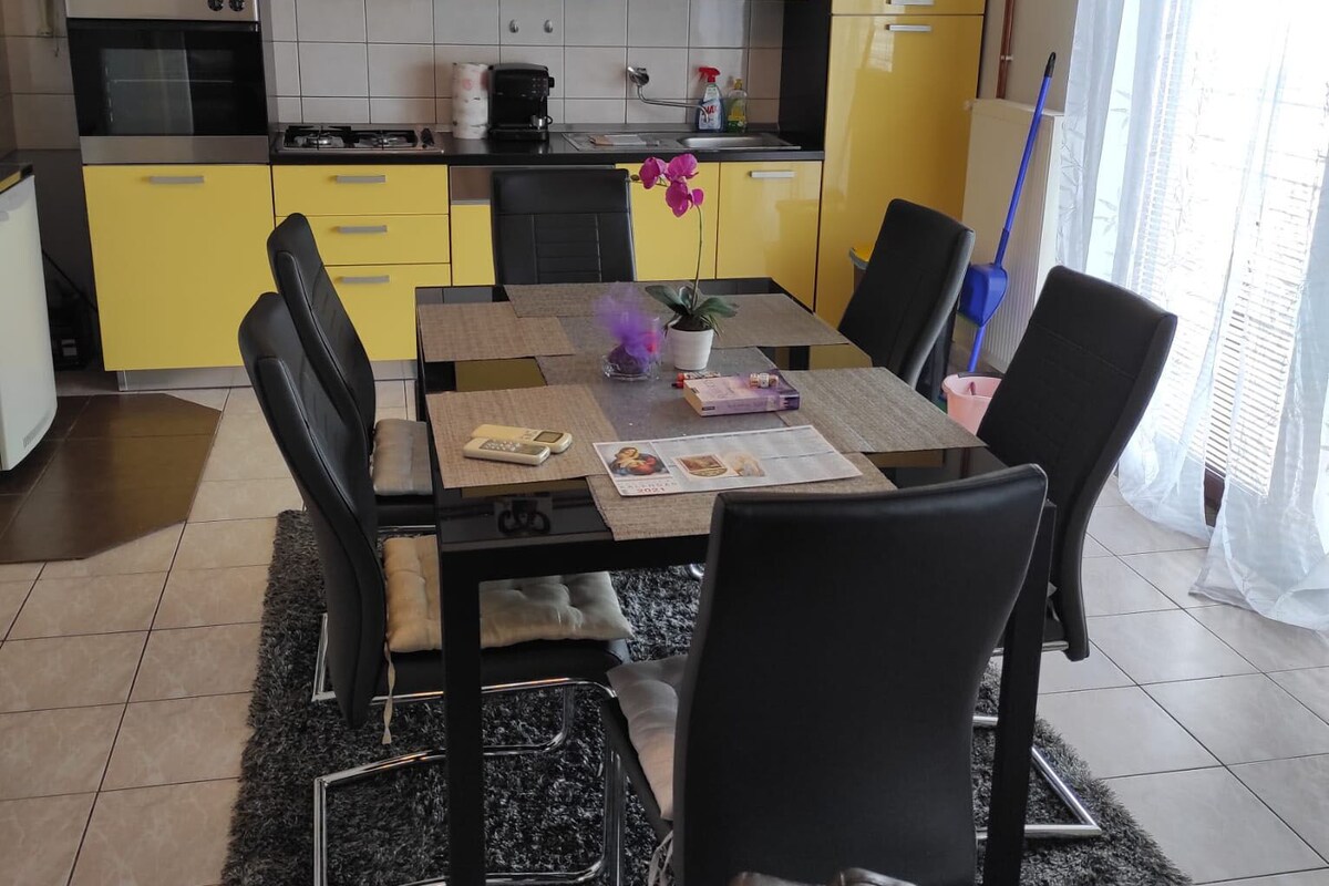 A modern kitchen with yellow cabinets, a dining table with chairs, and a microwave.
