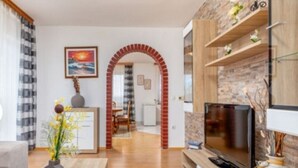 Een woonkamer met een televisie, een open haard en een eethoek op de achtergrond.