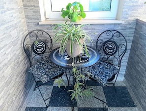 A small outdoor seating area with a round table and two chairs, surrounded by potted plants. - House Mira (Buje)