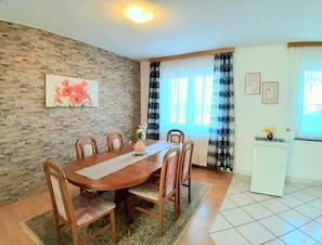 A dining area with a wooden table and chairs, a brick wall, and a window with curtains. - House Mira (Buje)