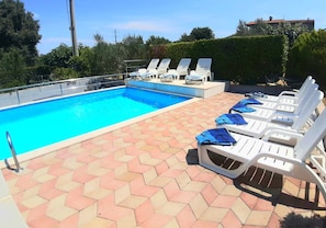 A swimming pool with lounge chairs and a tiled deck. - House Mira (Buje)