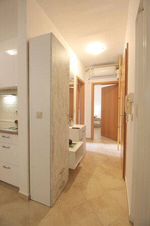 Ein Hotelgang mit einem weißen Kleiderschrank, einem Schminktisch mit Spiegel und einer Holztür zu einem anderen Raum.
