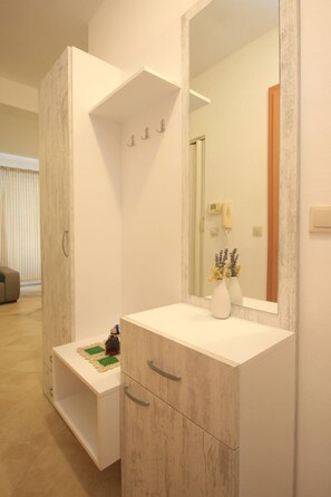 Un baño moderno con un espejo grande, un tocador blanco y un armario de madera.