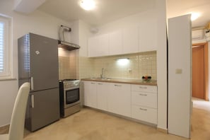 Eine kleine Küche mit Kühlschrank, Backofen und Spüle.