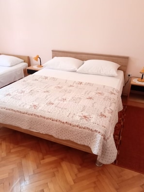 A bedroom with a large bed, two bedside tables, and a wooden floor.