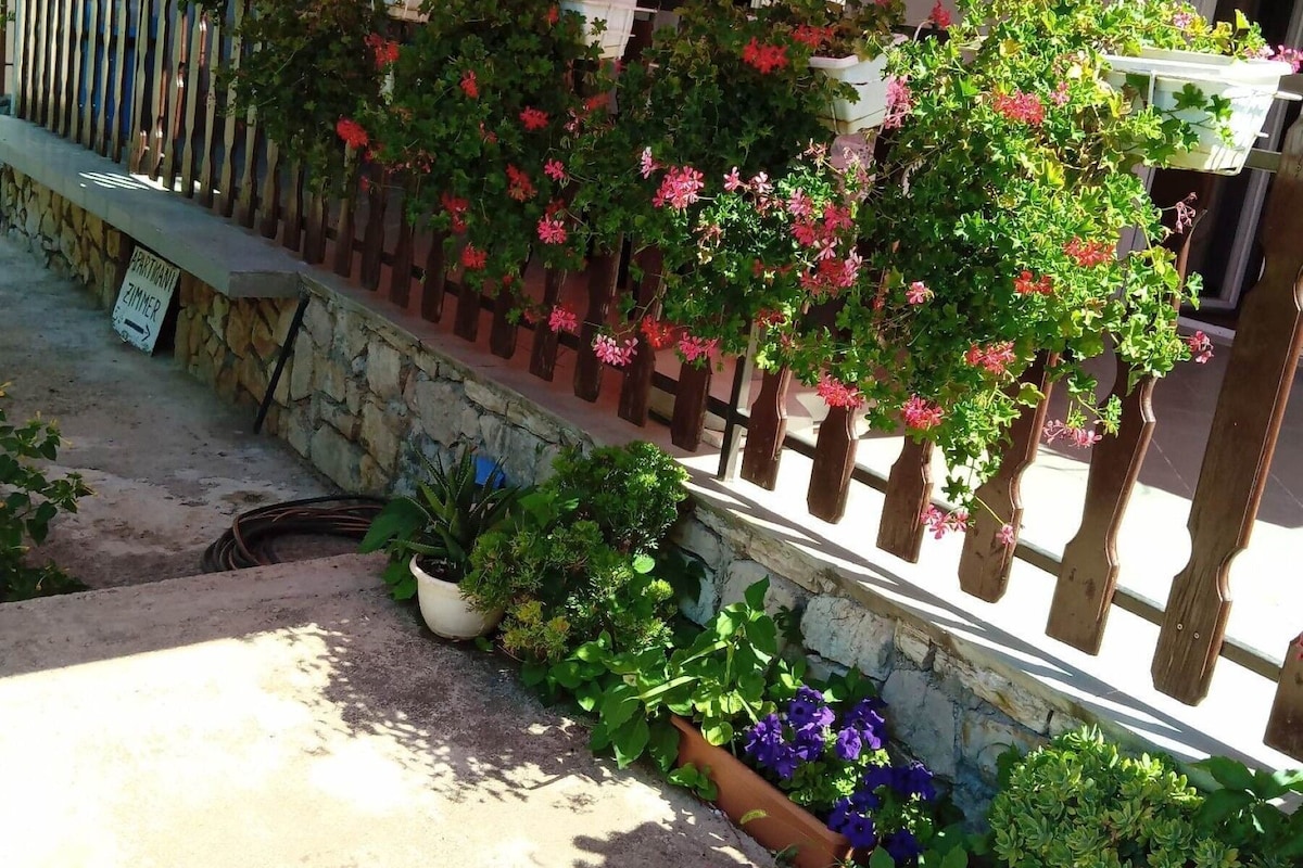 A building with a red awning, a stone wall, and various potted plants.
