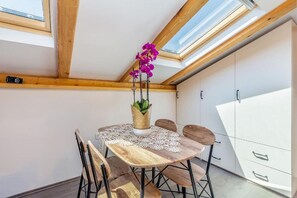 Ein Essbereich mit Tisch, Stühlen, einer Vase mit Blumen und einem Oberlicht.