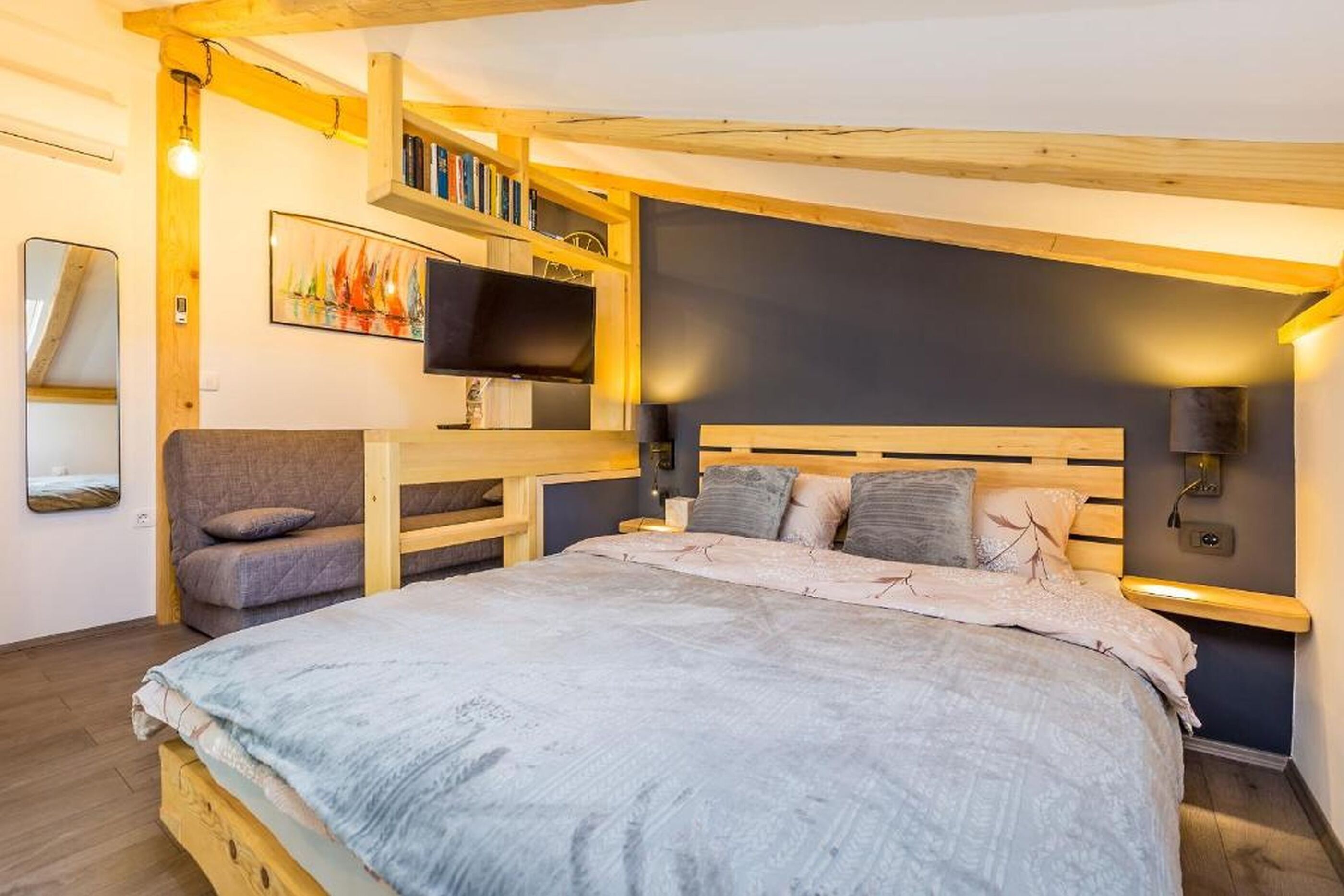 A bedroom with a bed, a TV, a bookshelf, and a desk.