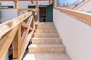 Una escalera de madera con escalones de piedra que conduce a una habitación con una puerta con contraventanas verdes.
