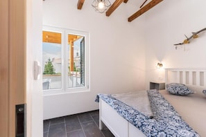 Un dormitorio con cama, ventana, luz empotrada en la pared y vistas al exterior.