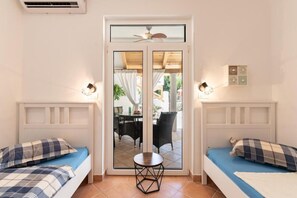 Una habitación con dos camas, una mesa y vistas a través de un ventanal.