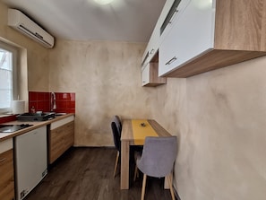 Eine kompakte Küche mit Holzarbeitsplatte, einer Spüle und einem Essbereich mit Tisch und Stühlen.