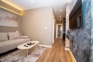 Ein modernes Wohnzimmer mit einer Couch, einem Couchtisch und einem an der Wand montierten Fernseher.