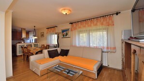 Una sala de estar con sofá, una mesa de centro de vidrio y un comedor con sillas y una mesa.