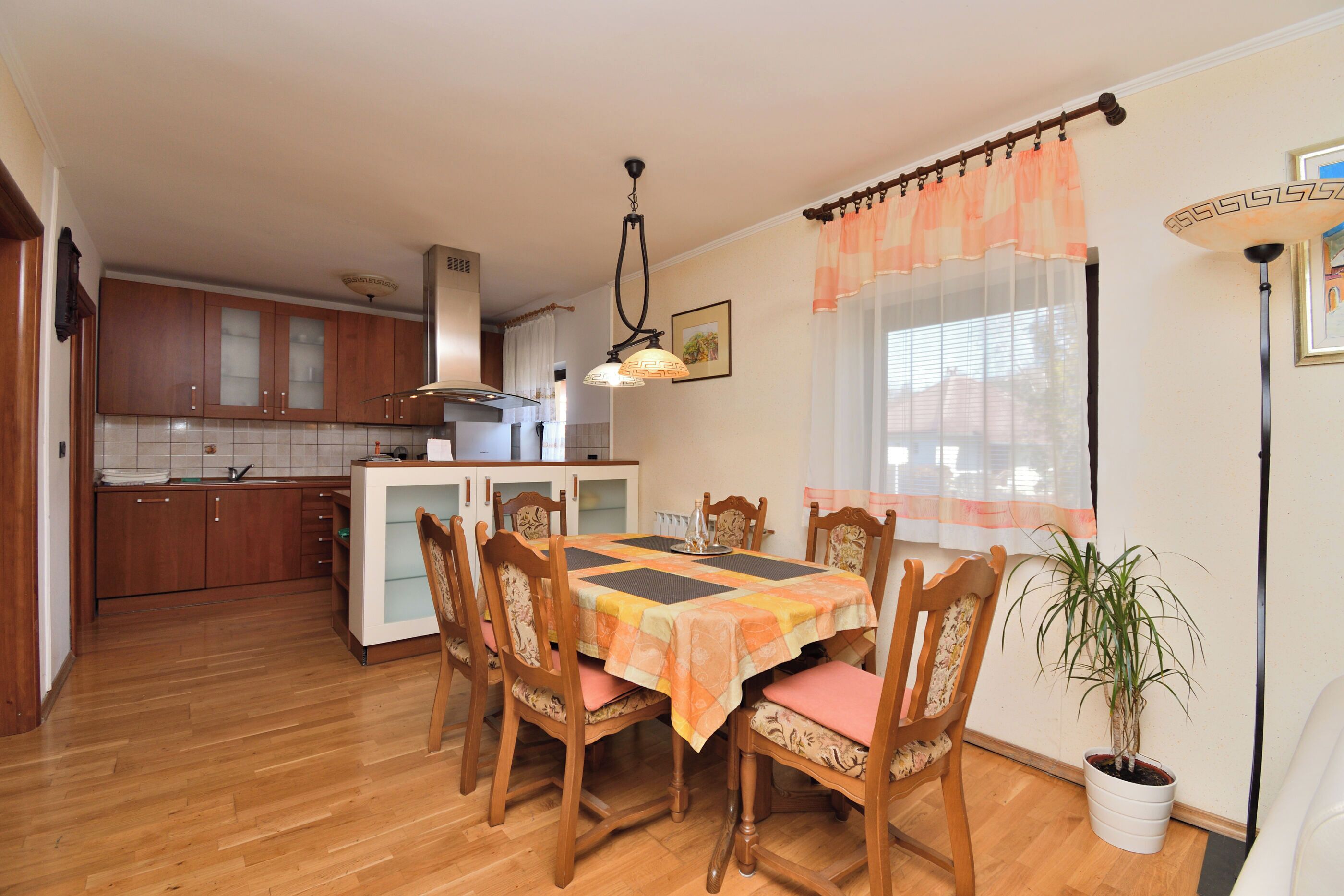 A dining area with a table set for four, surrounded by wooden chairs with cushioned seats.