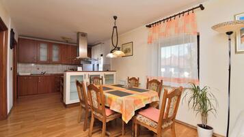 A dining area with a table set for four, surrounded by wooden chairs with cushioned seats.