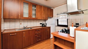 Una cocina con armarios de madera, un lavamanos de acero inoxidable, una estufa y un refrigerador.