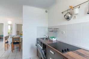 Eine moderne Küche mit einer Holzausziehtheke, einem integrierten Geschirrspüler und einer hängenden Küchenutensilienstange.